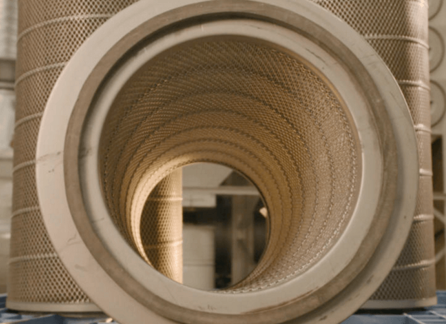 A set of three replacement cartridge filters sitting in front of an industrial dust collection system.