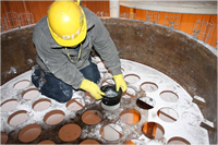 A technician wearing protective gear and replacing ProPulse baghouse pleated bag filters.